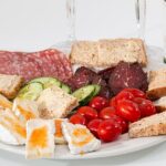 Savory charcuterie platter with cured meats, cherry tomatoes, cucumber, cheese, and crackers for healthy living and stretching routines.