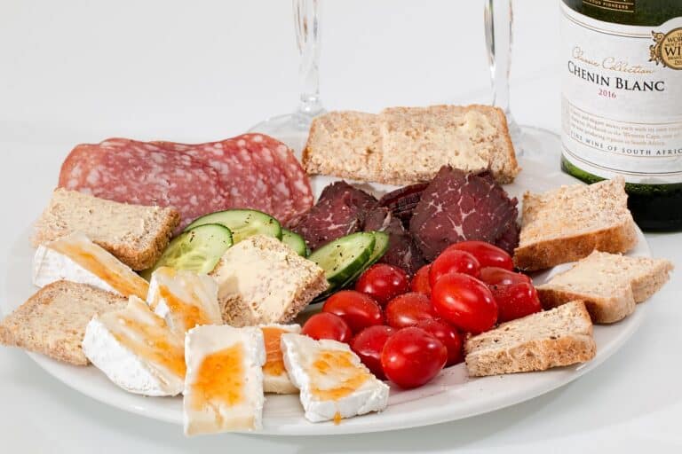 Savory charcuterie platter with cured meats, cherry tomatoes, cucumber, cheese, and crackers for healthy living and stretching routines.