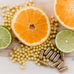 Fresh citrus fruits including orange and lime slices with dietary supplements and herbal capsules on a wooden surface. Perfect for promoting immune health, vitamin C, and natural wellness.