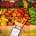 Fresh colorful bell peppers, tomatoes, zucchini, and squash at a local farmers market, showcasing healthy produce options with vibrant display for outdoor shopping.