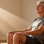 Relaxed senior man practicing seated stretching exercises in natural sunlight for improved flexibility and joint health. Ideal for staying active and healthy at any age.